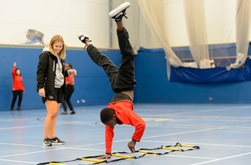 A boy performs a cartwheel in a school PE lesson