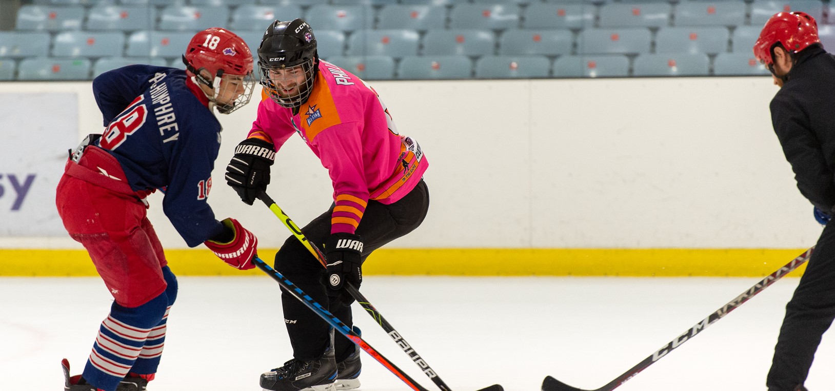 Three ice hockey players compete for the puck.