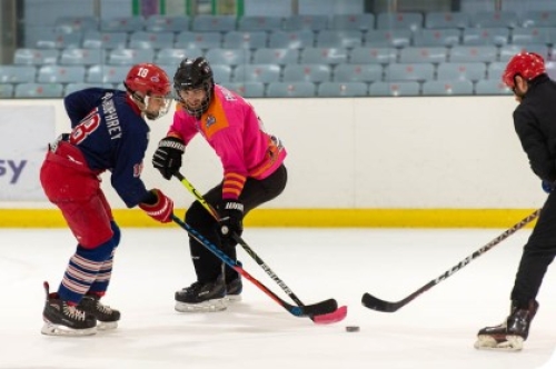 Three ice hockey players compete for the puck.