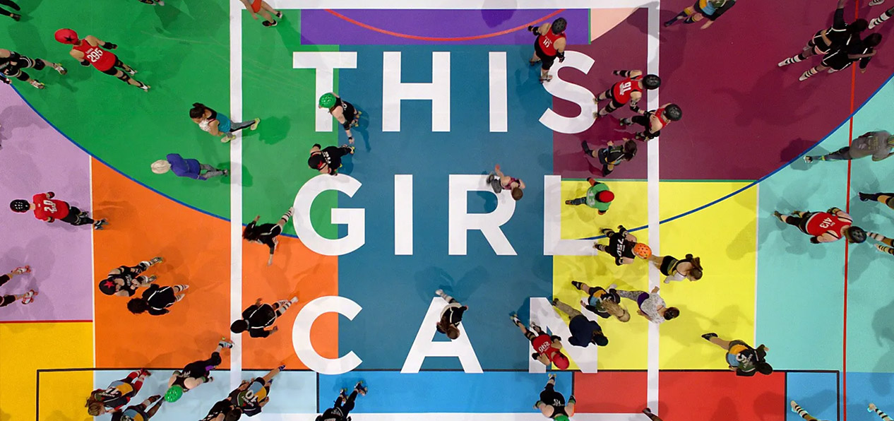 Aerial view of a group of women on a colourful pitch with the This Girl can logo in white in the middle.