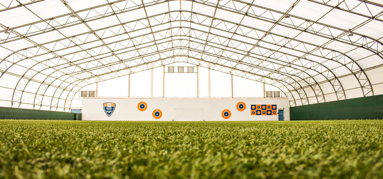 Grass-level shot of an indoor football pitch.