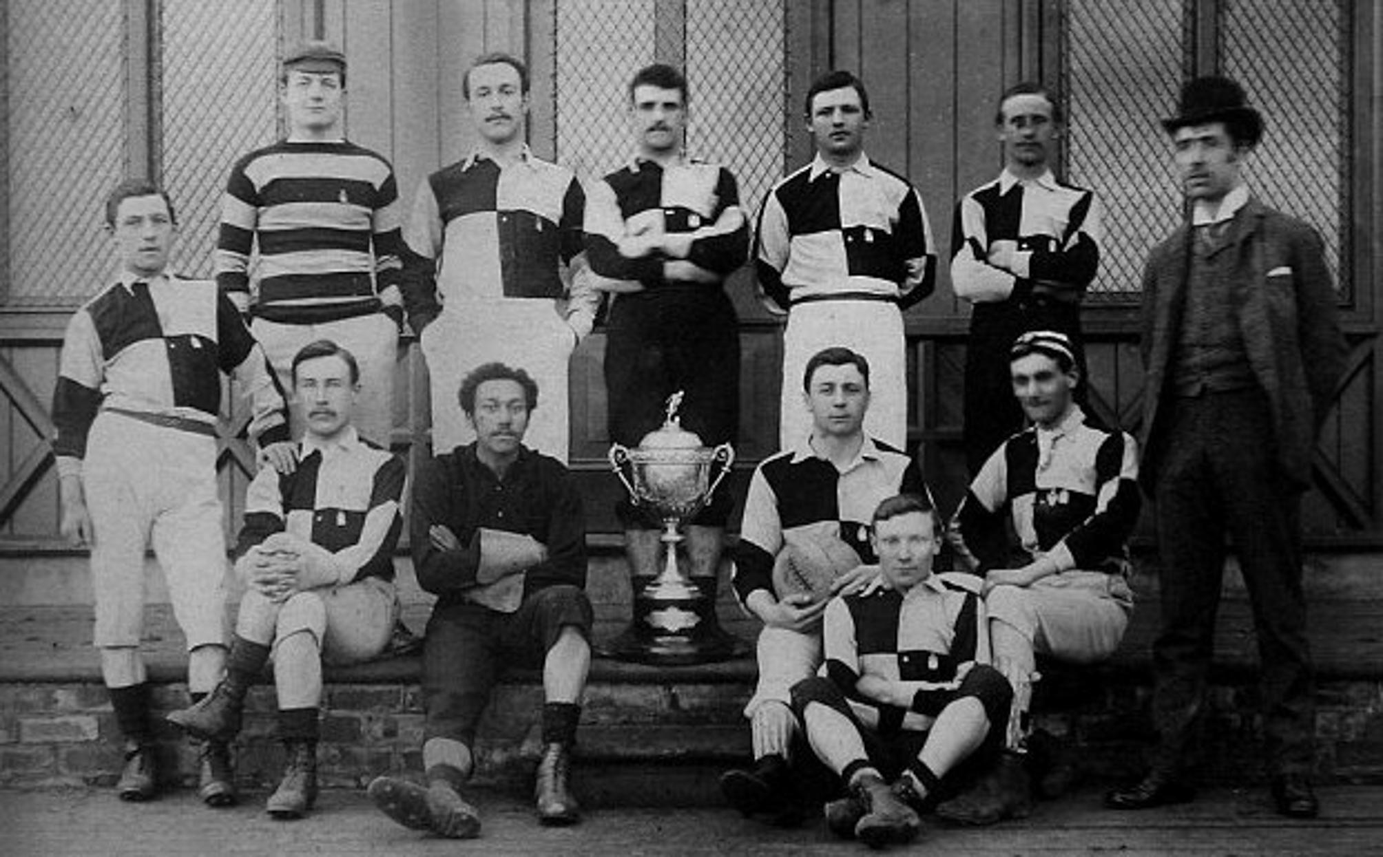 Picture of Arthur Wharton , the world's first black professional player, with his teammates from Sheffield United in 1895, next to a trophy.